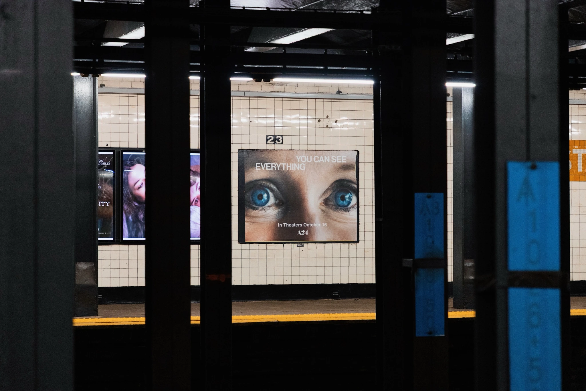 A24 You Can See Everything poster inside a New York subway station featuring an intense pair of blue eyes.