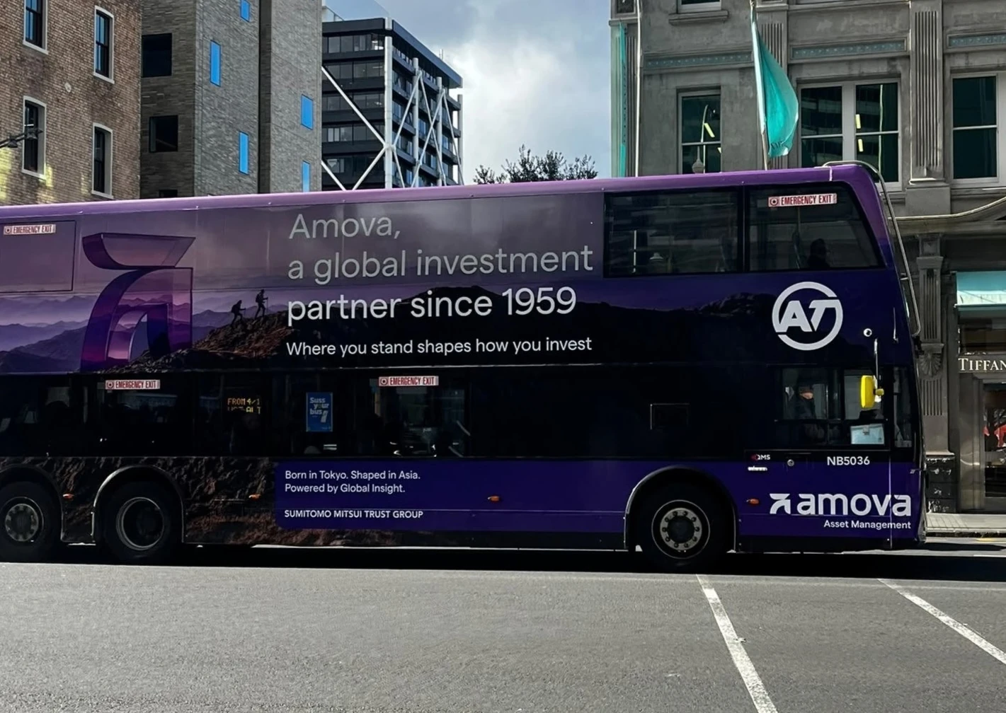 Purple Amova Asset Management double-decker bus wrap in New Zealand carrying the line Amova, a global investment partner since 1959.