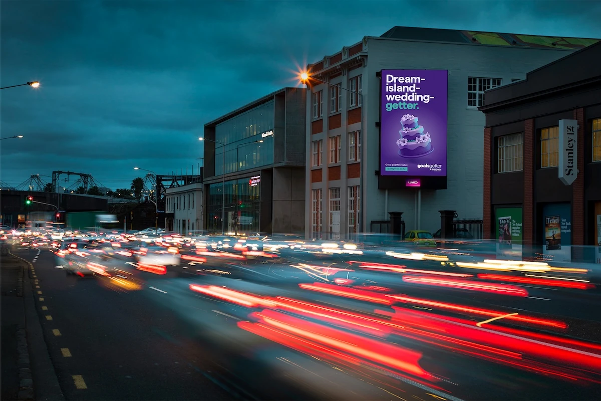GoalsGetter digital billboard in New Zealand featuring a purple wedding cake and the line Dream-island-wedding-getter as part of Amova’s investment platform campaign.