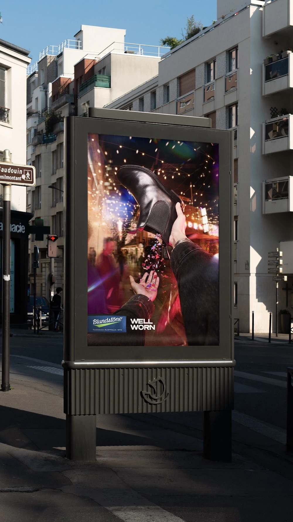 Vertical Blundstone Well Worn street poster showing a black boot against a colourful nightlife scene.