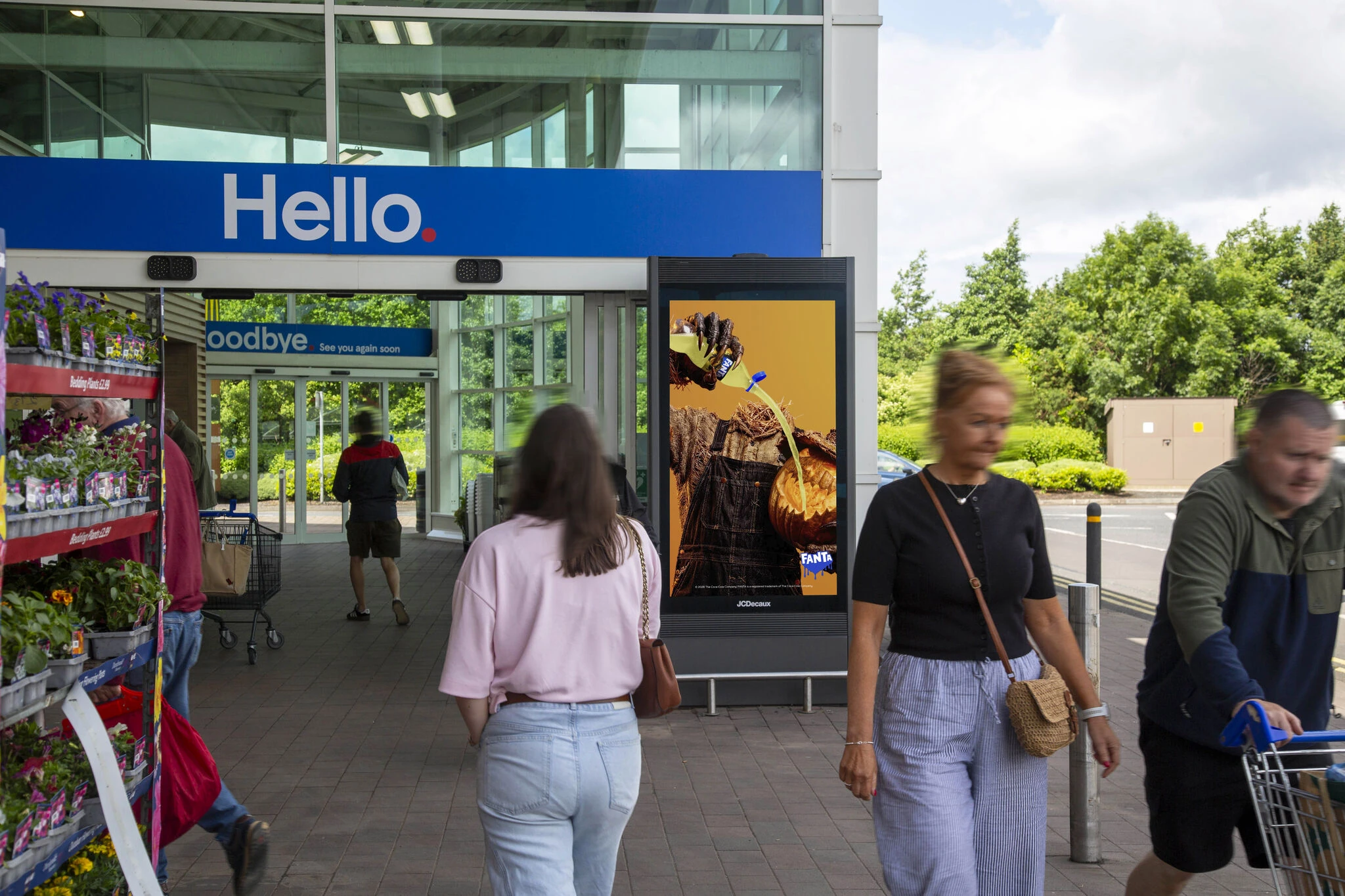 Fanta Halloween retail DOOH campaign featuring a pumpkin and orange beverage creative outside a busy store entrance.