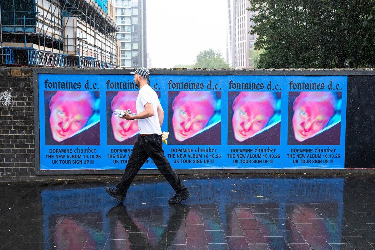 Repeated Fontaines D.C. Dopamine Chamber posters displayed along a London street wall in wet weather.