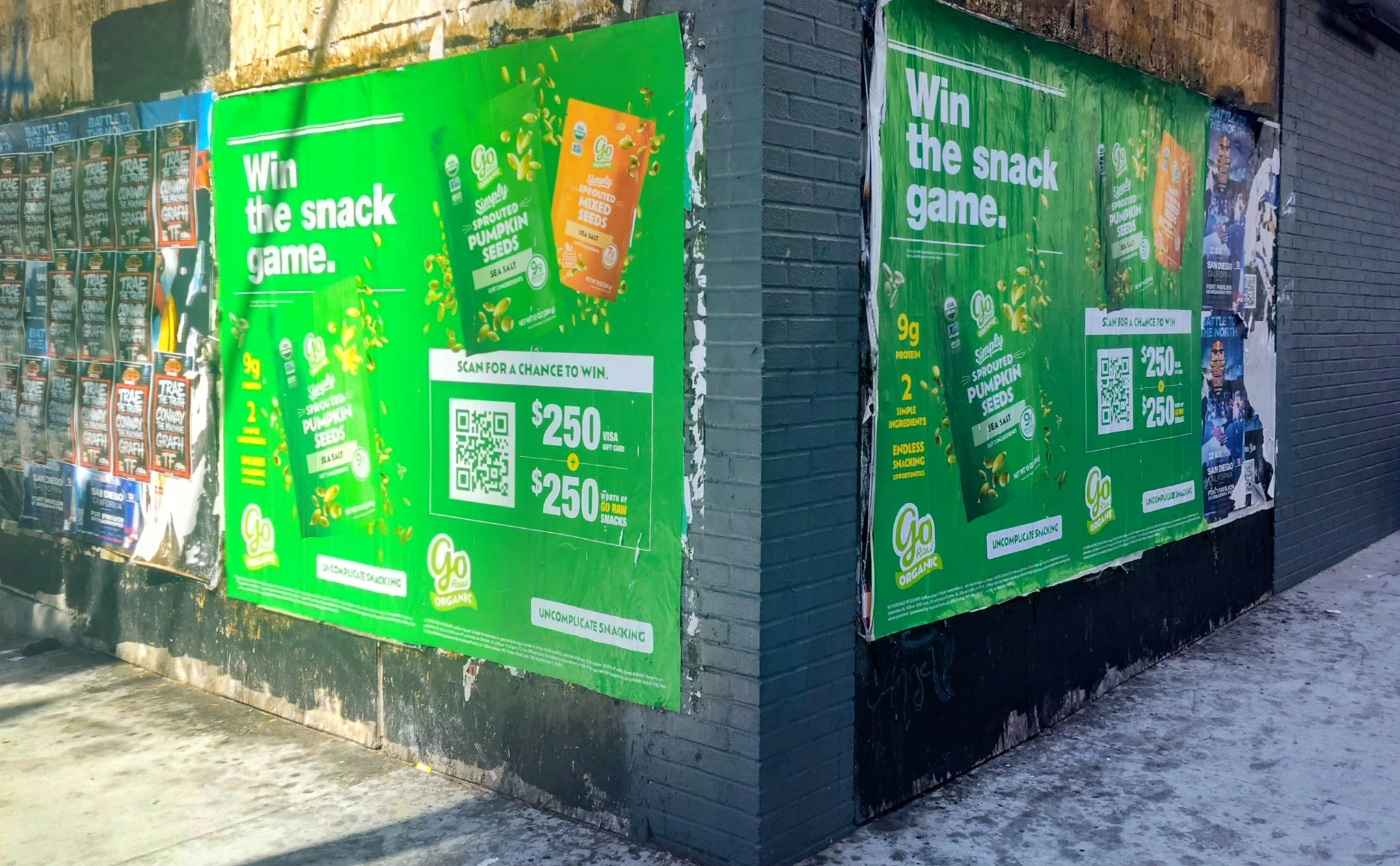 Green and black poster installations on a San Diego street wall alongside Grizzly creative agency messaging.