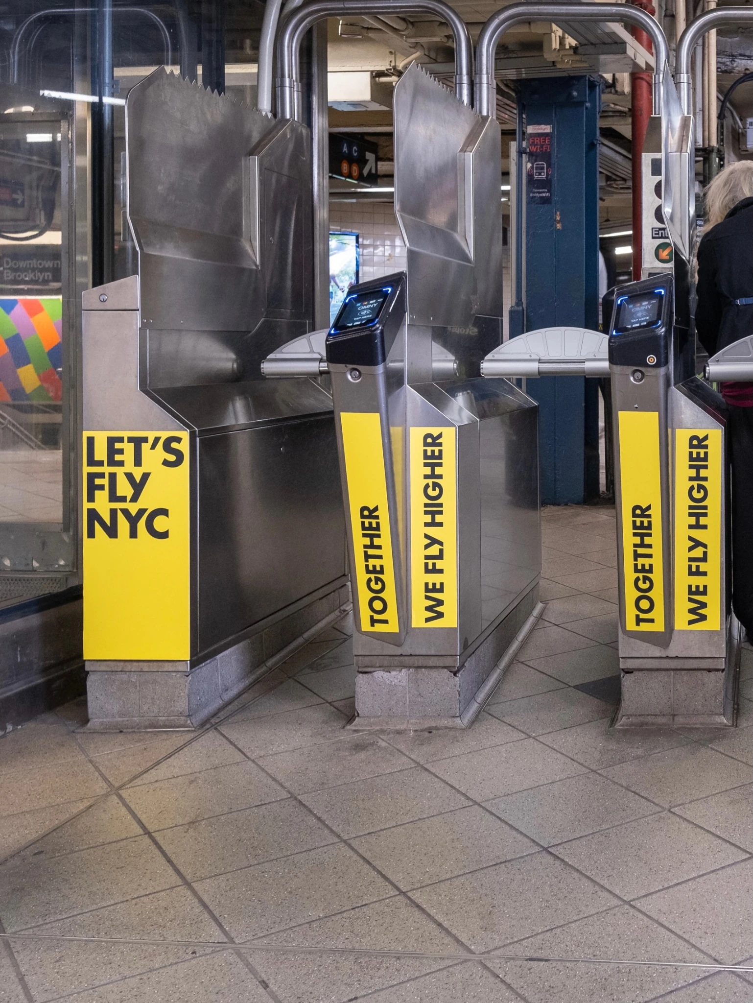 HOKA branded New York subway turnstiles with Lets Fly NYC and Together We Fly Higher messaging.