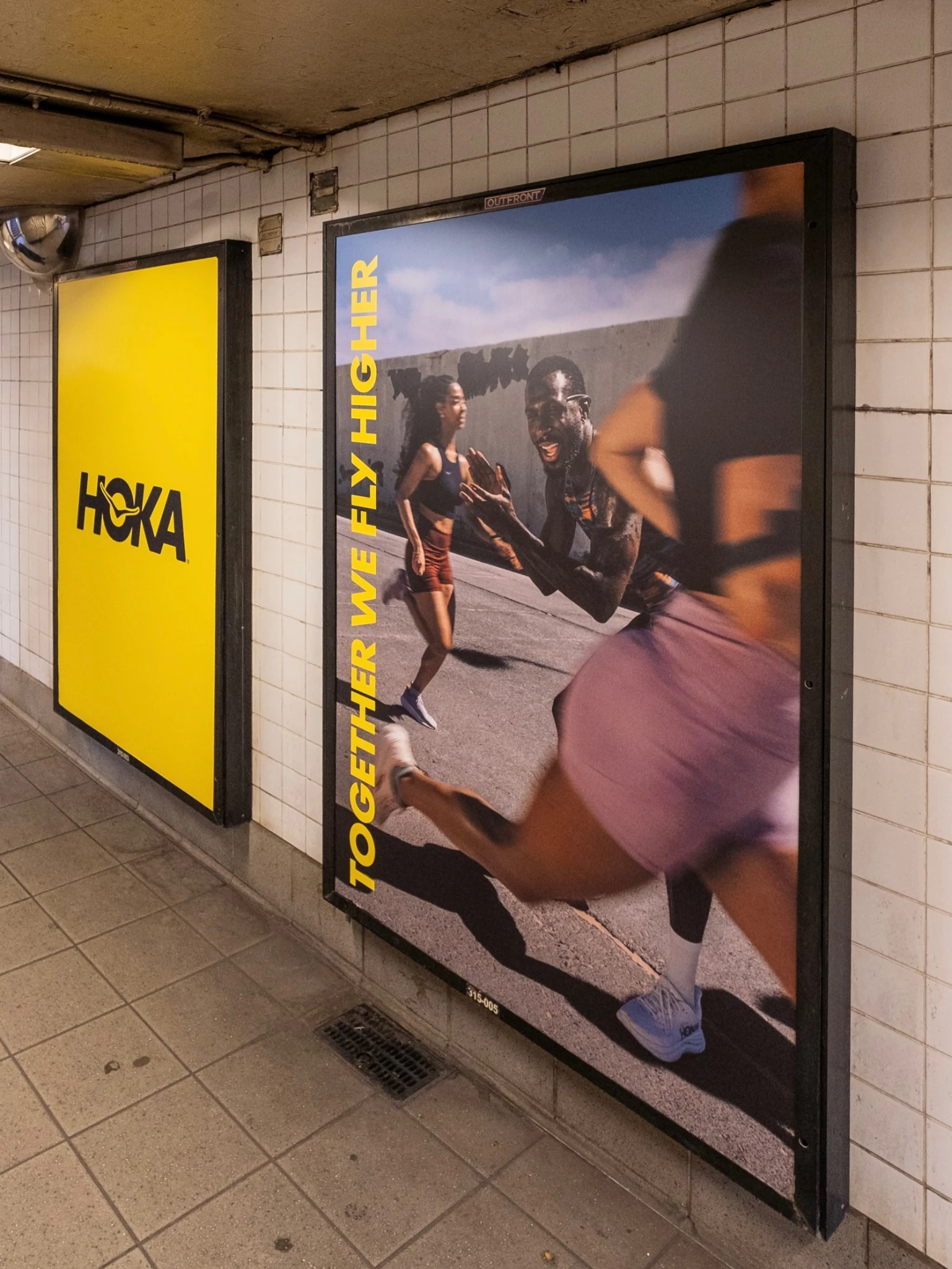 HOKA subway poster featuring runners and Together We Fly Higher messaging at Columbus Circle in New York.