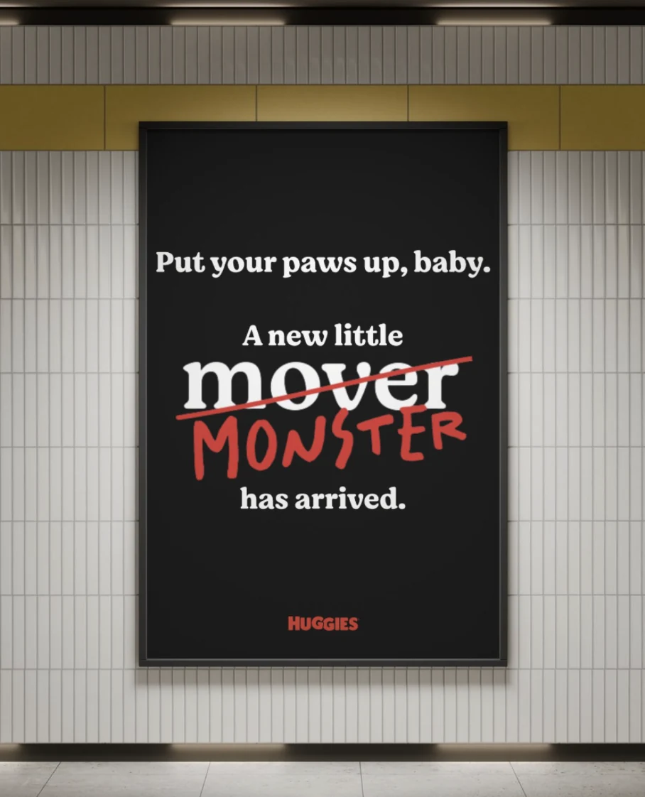 Huggies outdoor advertisement on a tiled wall with the headline Put your paws up, baby and the phrase A new little mover has arrived, with mover crossed out and replaced by monster in red.