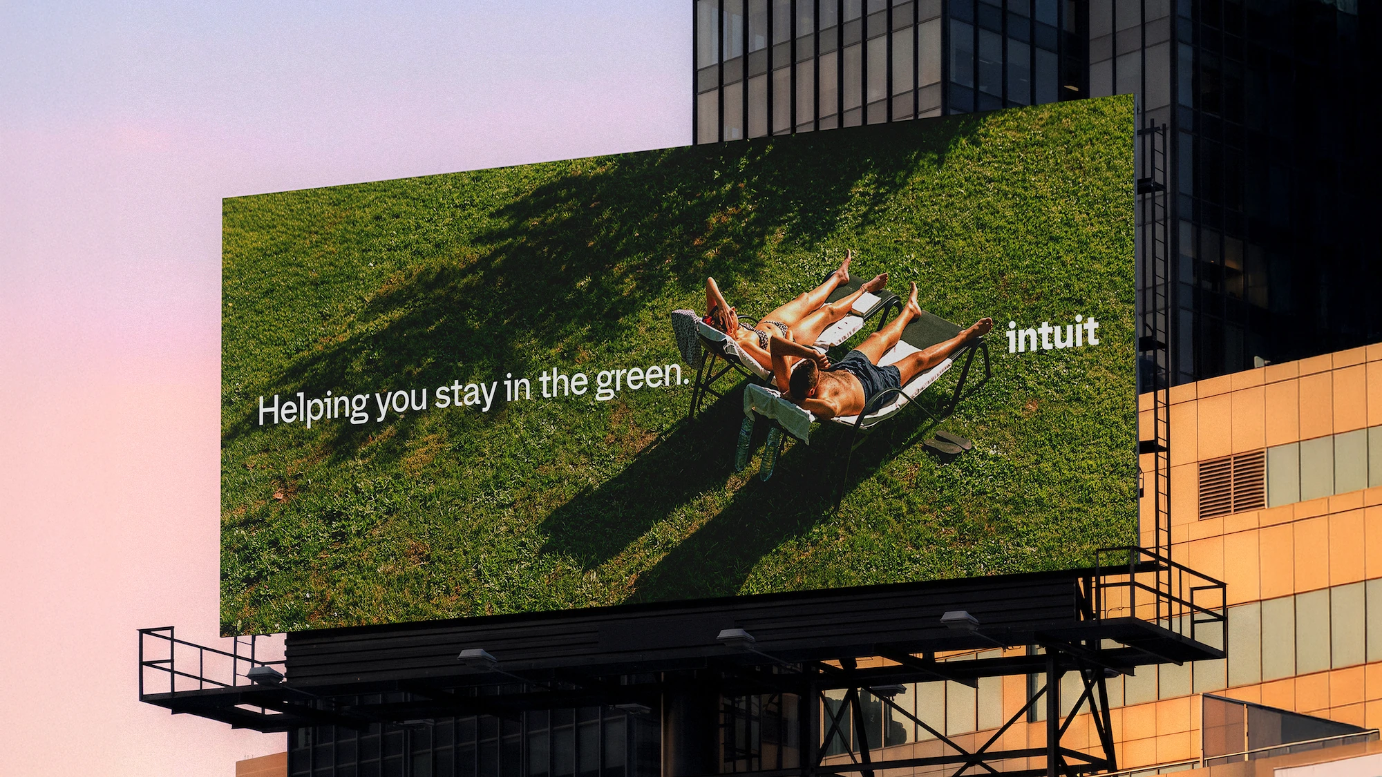 Intuit billboard showing two people relaxing on green grass with the line Helping you stay in the green and the Intuit logo.