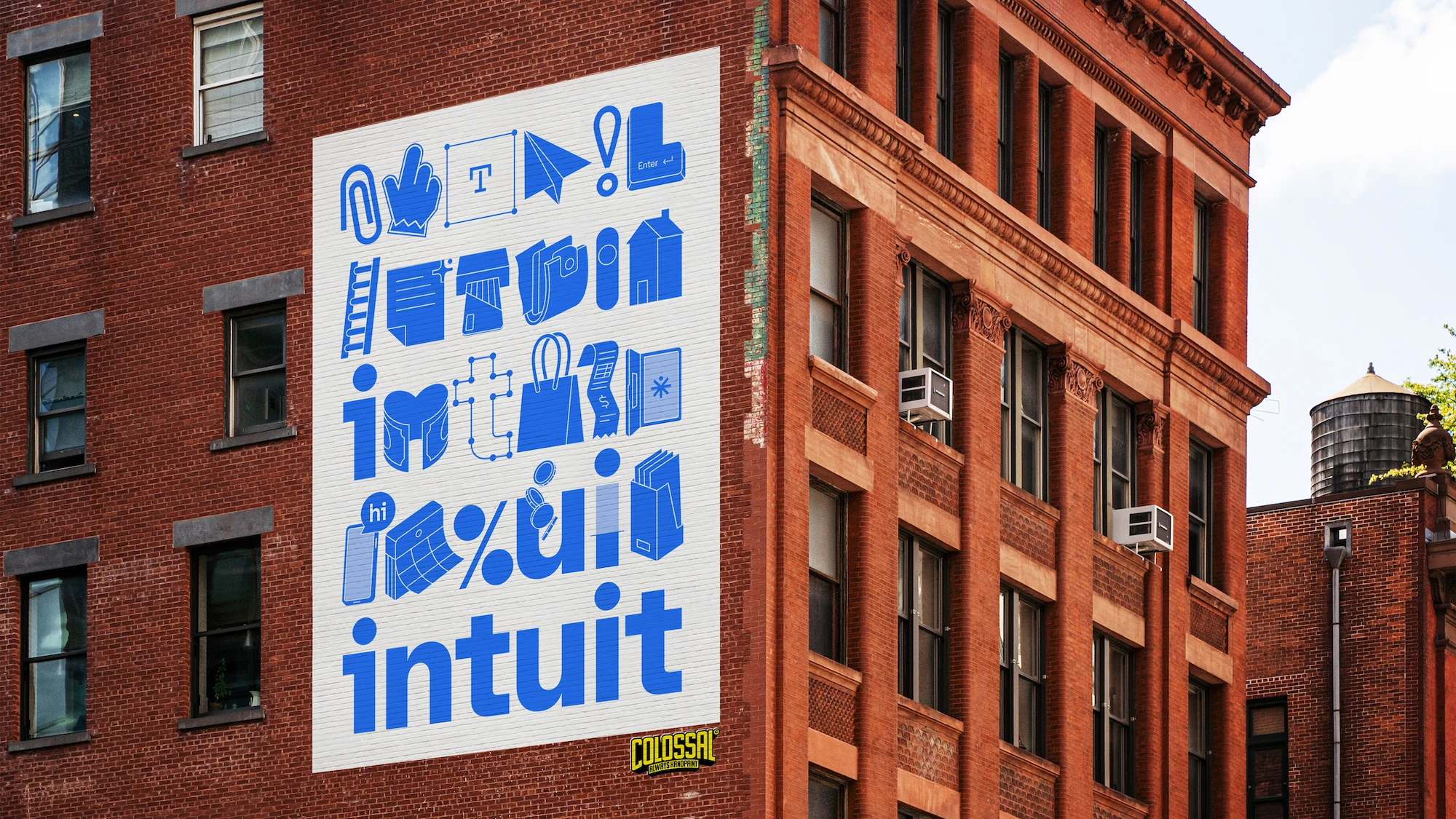Large Intuit wallscape advertisement on a brick building featuring blue brand icons and the Intuit wordmark as part of the company’s new visual identity.