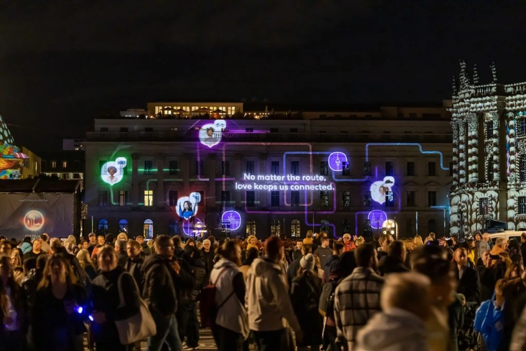 Crowds at Berlin Festival of Lights viewing Life360 Routes of Love projection with glowing route lines and the message No matter the route, love keeps us connected.