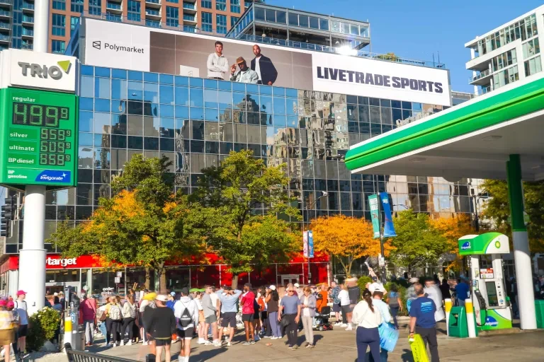 LIVETRADE SPORTS billboard mounted above a reflective building facade in Chicago during marathon-related city activity.