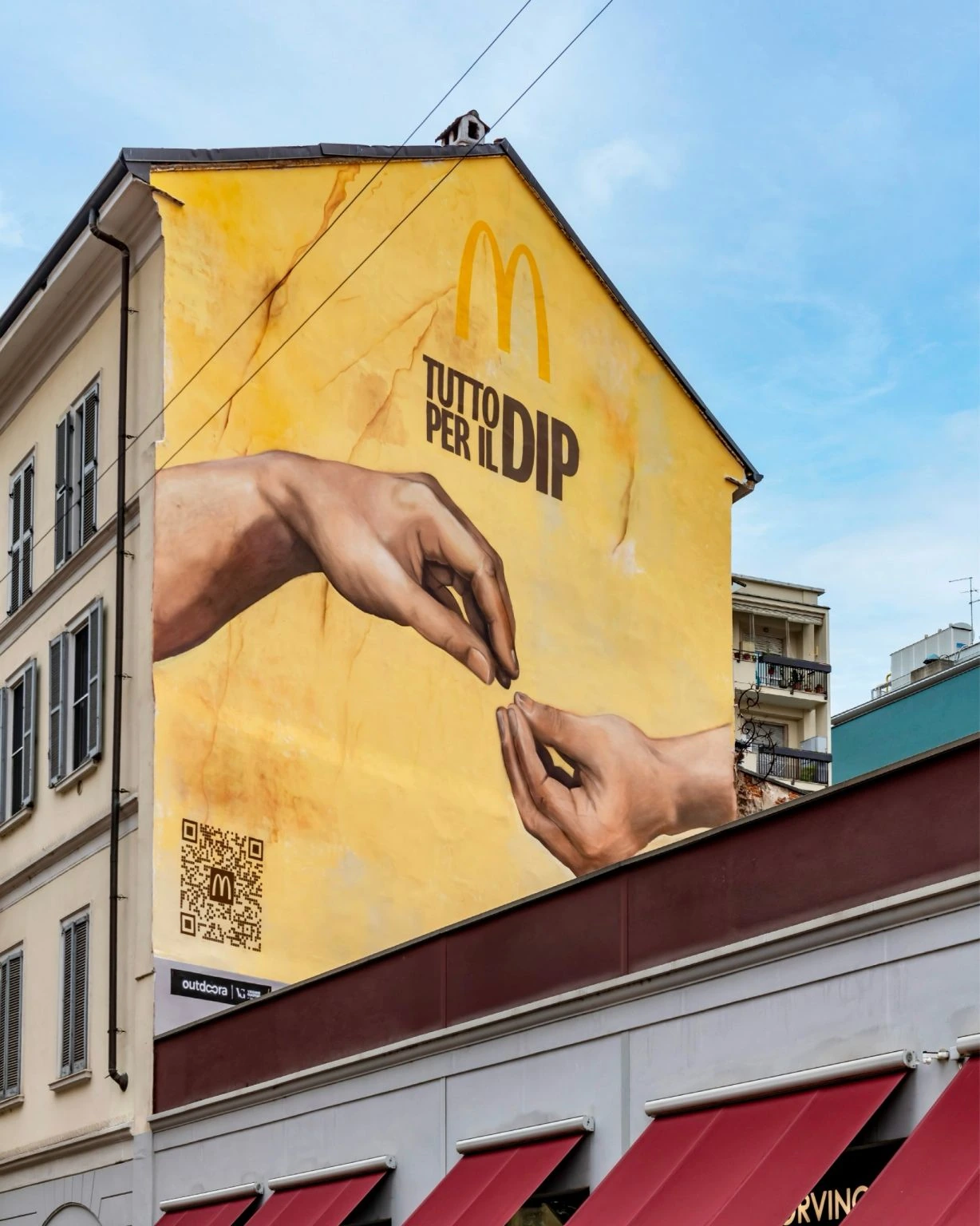 Close-up of the McDonald’s Tutto per il Dip mural on via Pasubio 6 in Milan featuring two hands and the campaign headline.