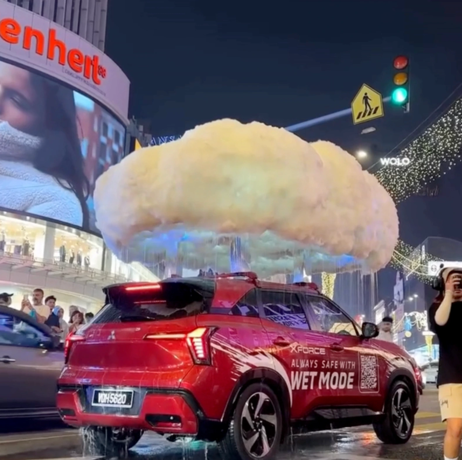 Mitsubishi Xforce parked in Kuala Lumpur under a giant artificial raincloud with water falling around the SUV.