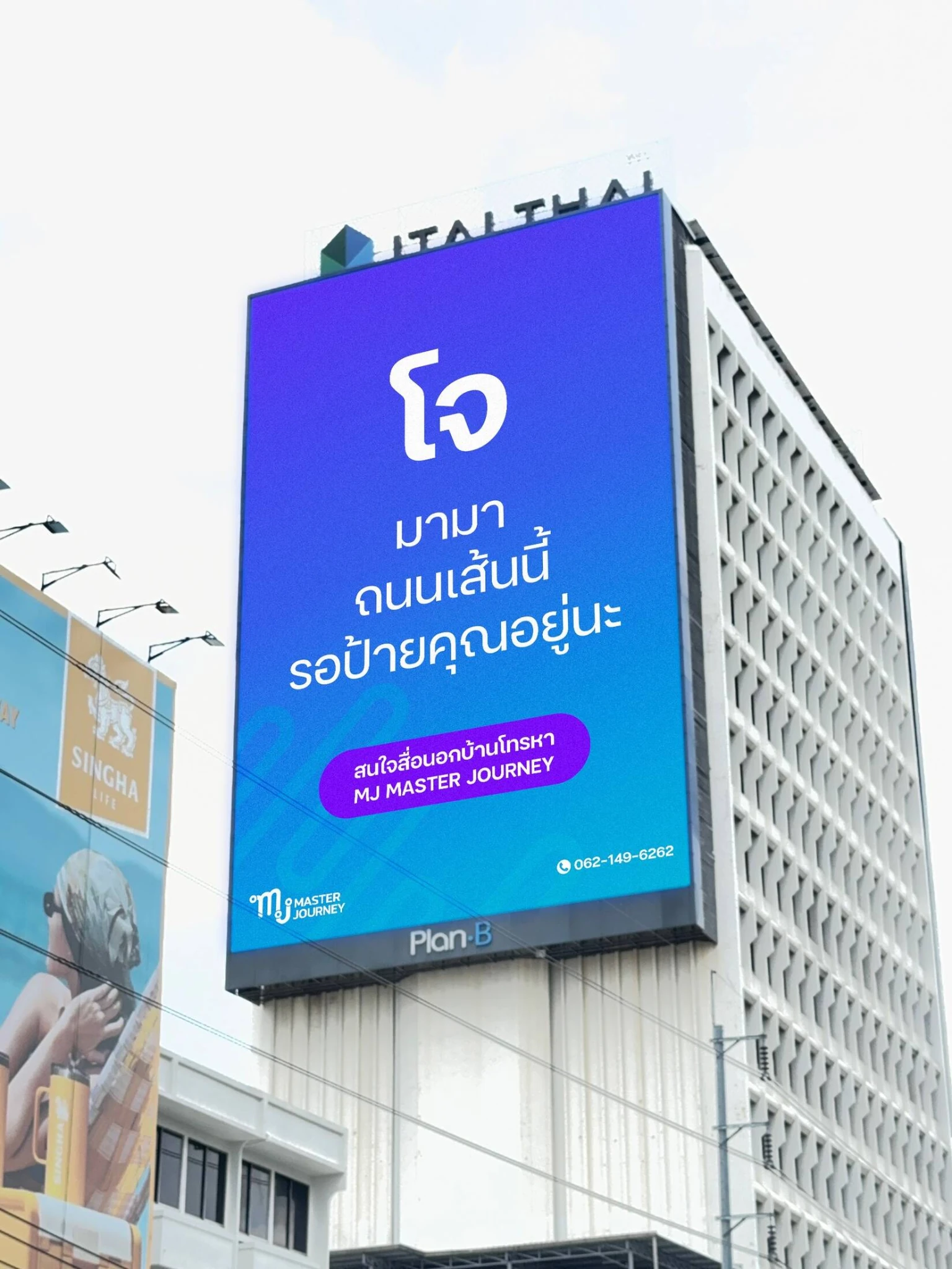 A tall blue MJ Master Journey billboard on the side of a building in Bangkok, featuring Thai copy and a clean gradient design as part of the One Eyeball Billboard campaign.
