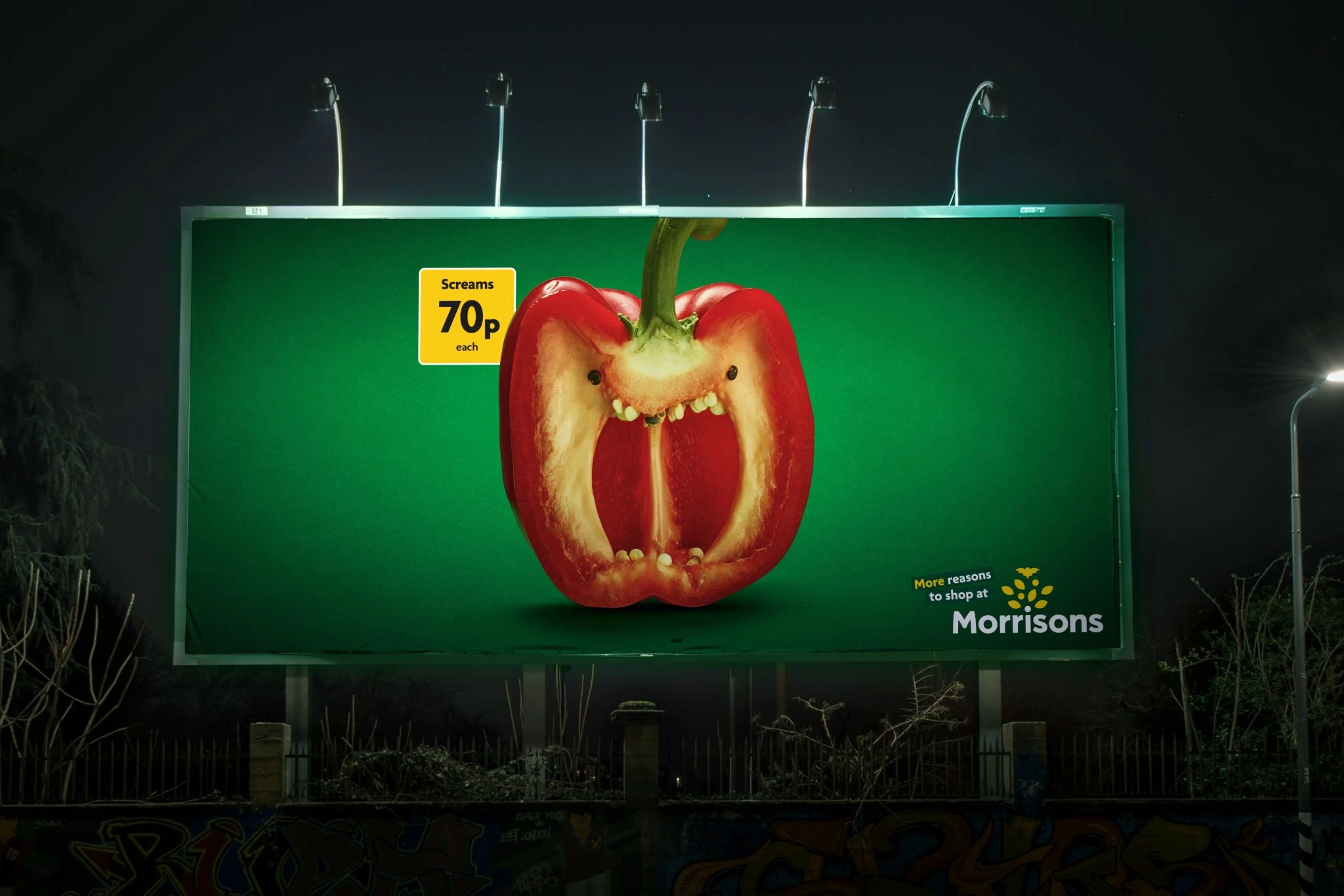 Night billboard for Morrisons showing a red pepper designed like a screaming face with a yellow price marker.