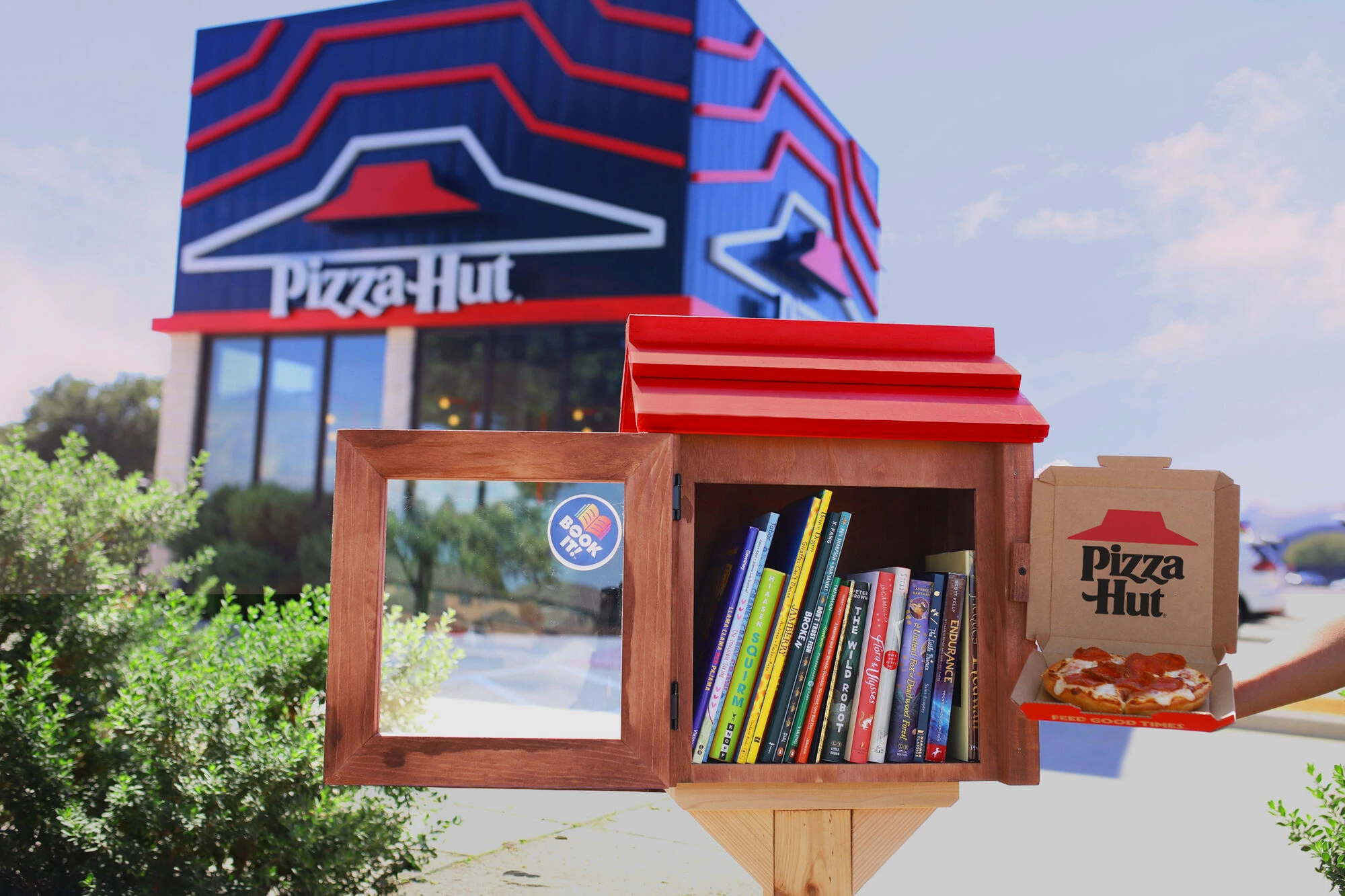 Pizza Hut Little Hut Library filled with books in front of a Pizza Hut restaurant.