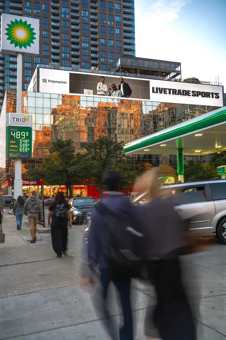 Daytime view of the LIVETRADE SPORTS billboard by Red Star Outdoor in Chicago with pedestrians and street traffic below.