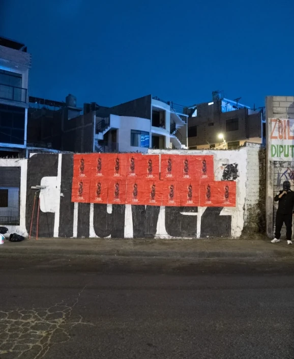A wall in Lima covered with multiple red Slipknot posters, creating a large-scale guerrilla street display at night.