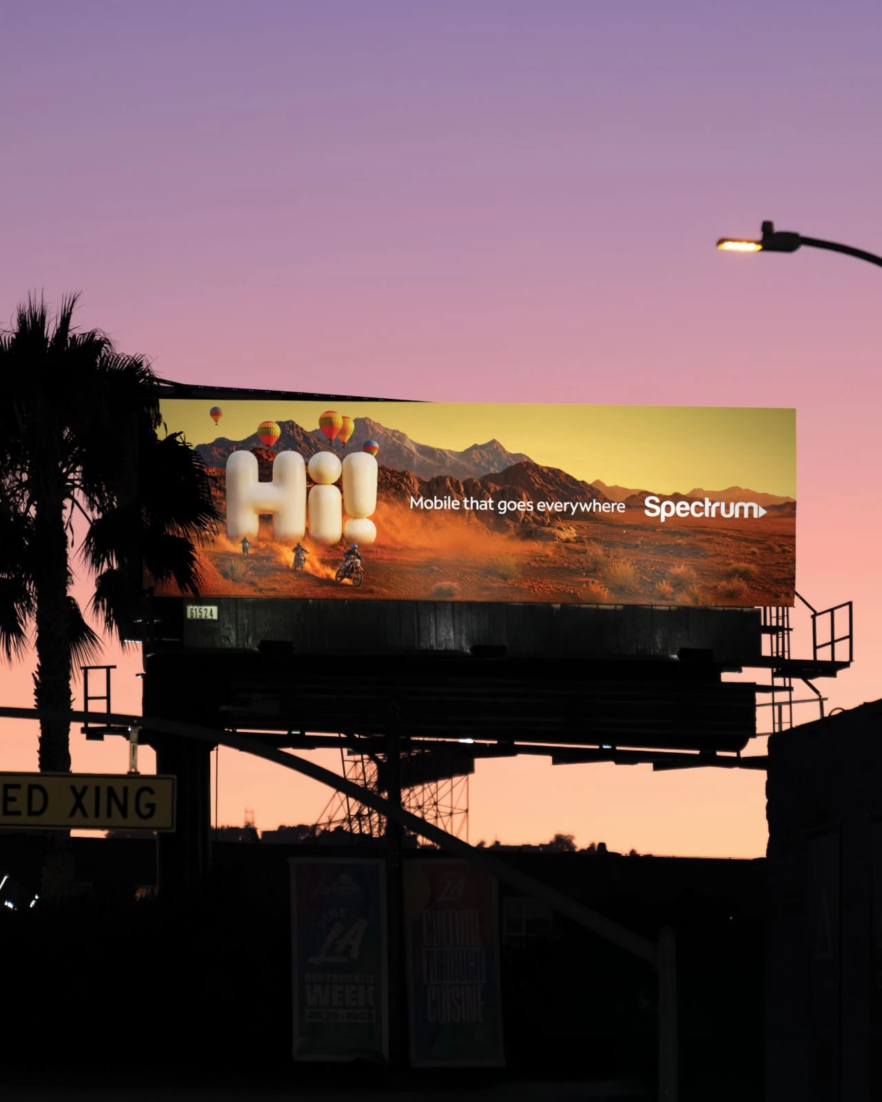 Spectrum billboard at dusk showing a giant inflatable Hi! in a desert landscape with motorcycles and the headline Mobile that goes everywhere.