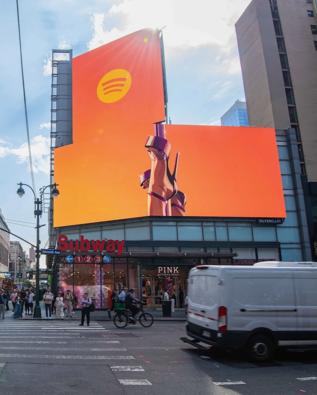 Large Spotify-branded GTA VI-style digital billboard above a Seventh Avenue subway entrance in Manhattan showing stylized raised legs in high heels against a bright orange background.