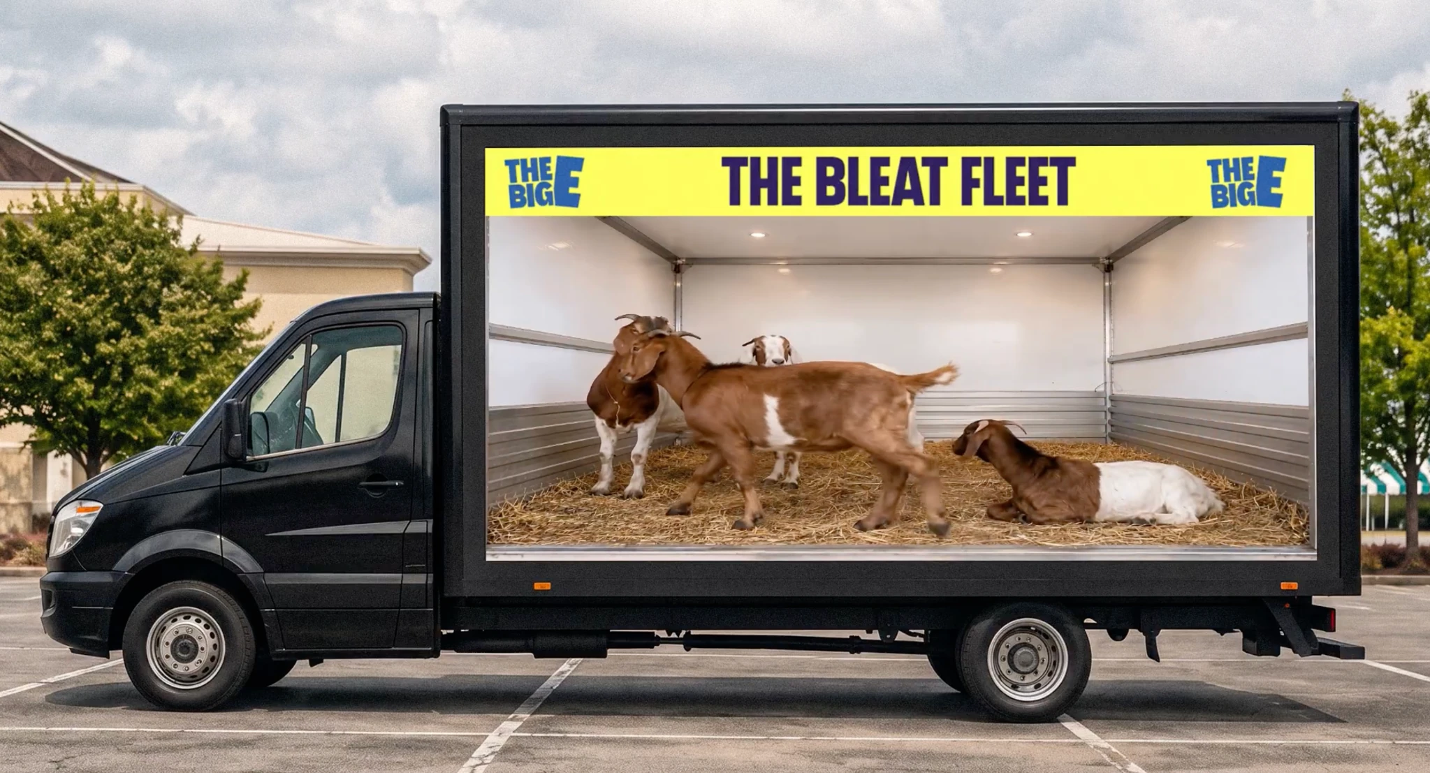 Mobile digital truck for The Big E labeled The Bleat Fleet, showing live goats inside a transparent display-style trailer filled with straw.