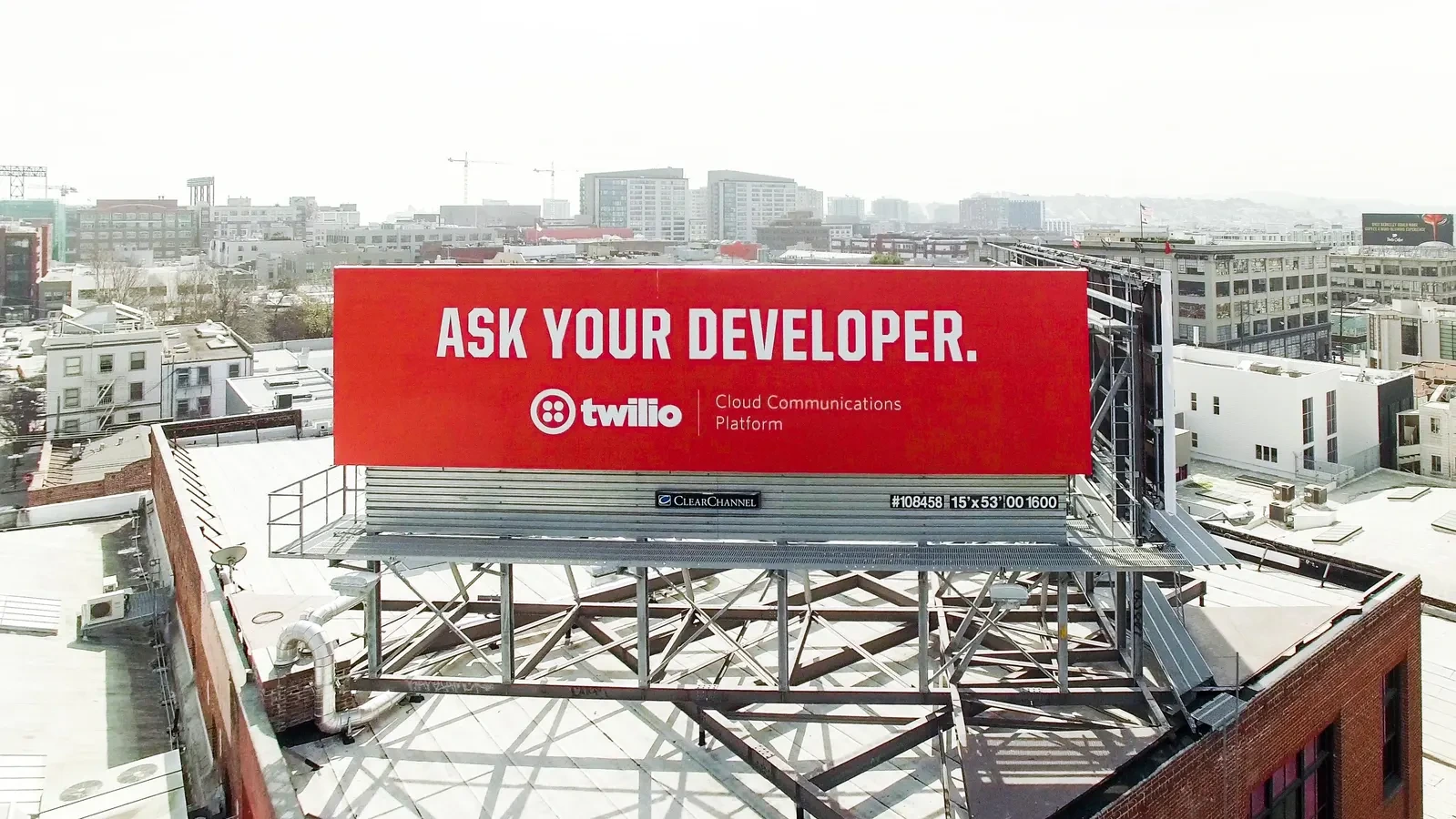 Twilio Ask Your Developer red billboard installed above an urban rooftop in San Francisco.