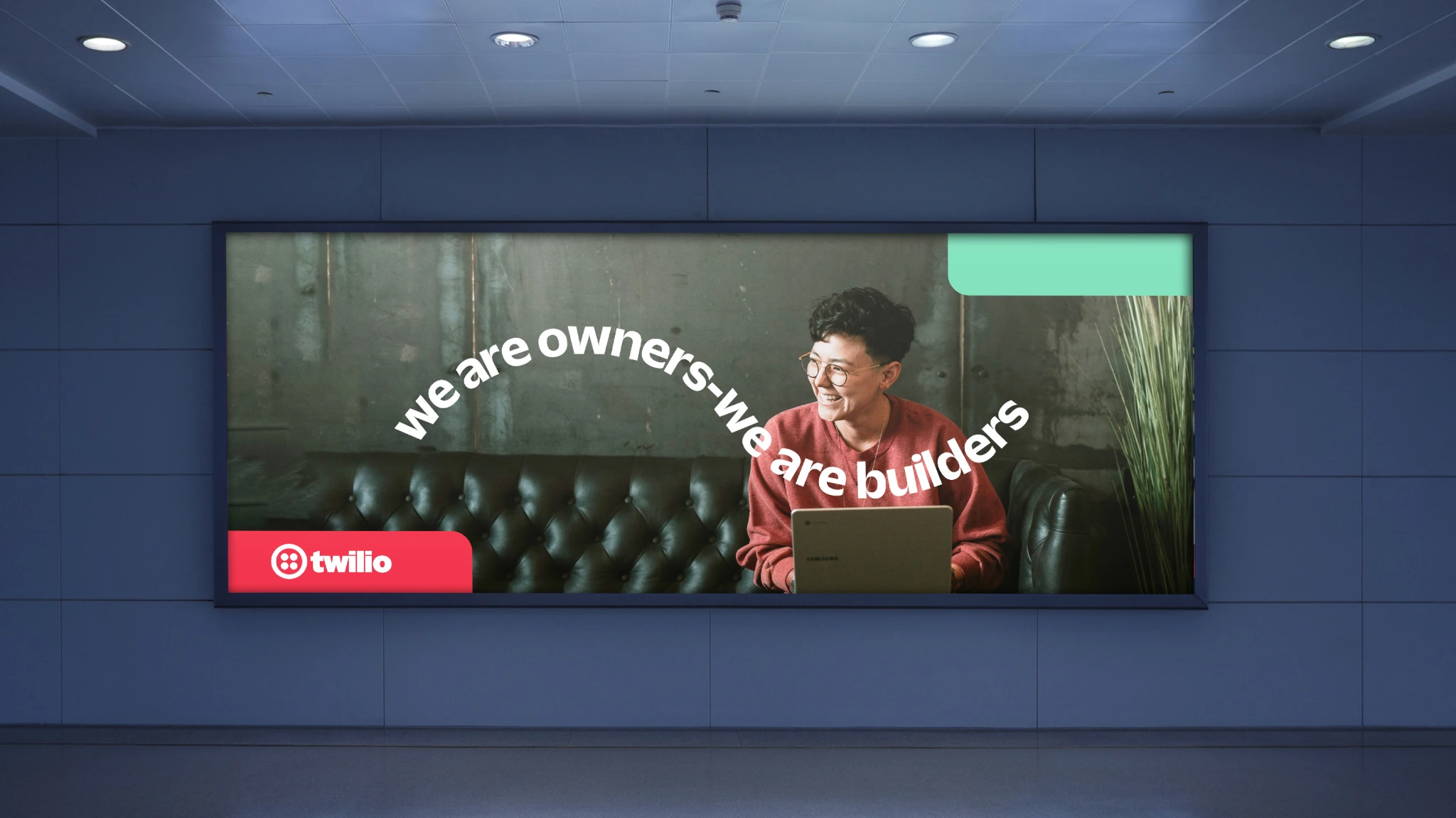 Twilio digital OOH creative reading We are owners, we are builders on a large indoor screen.