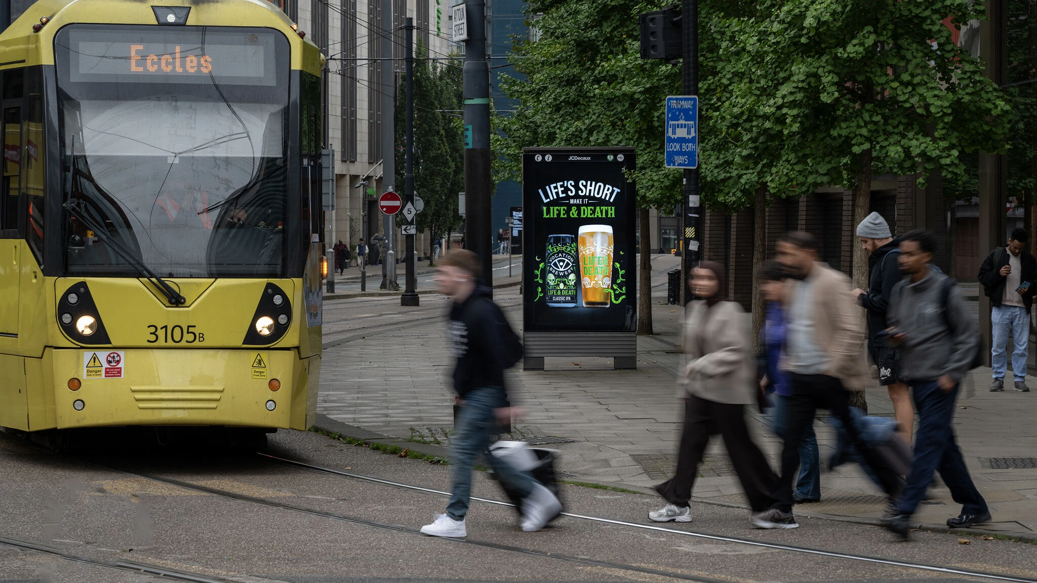Digital street furniture display promoting Vocation Brewery Life & Death IPA on a busy city street in Manchester.