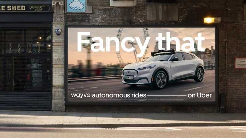 Large London billboard featuring a white Wayve autonomous vehicle on Uber with the headline Fancy that and the London Eye visible in the background.