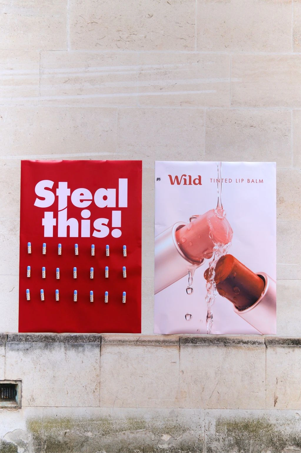 Two Wild campaign posters on a city wall, including the Steal this activation and a tinted lip balm product visual.